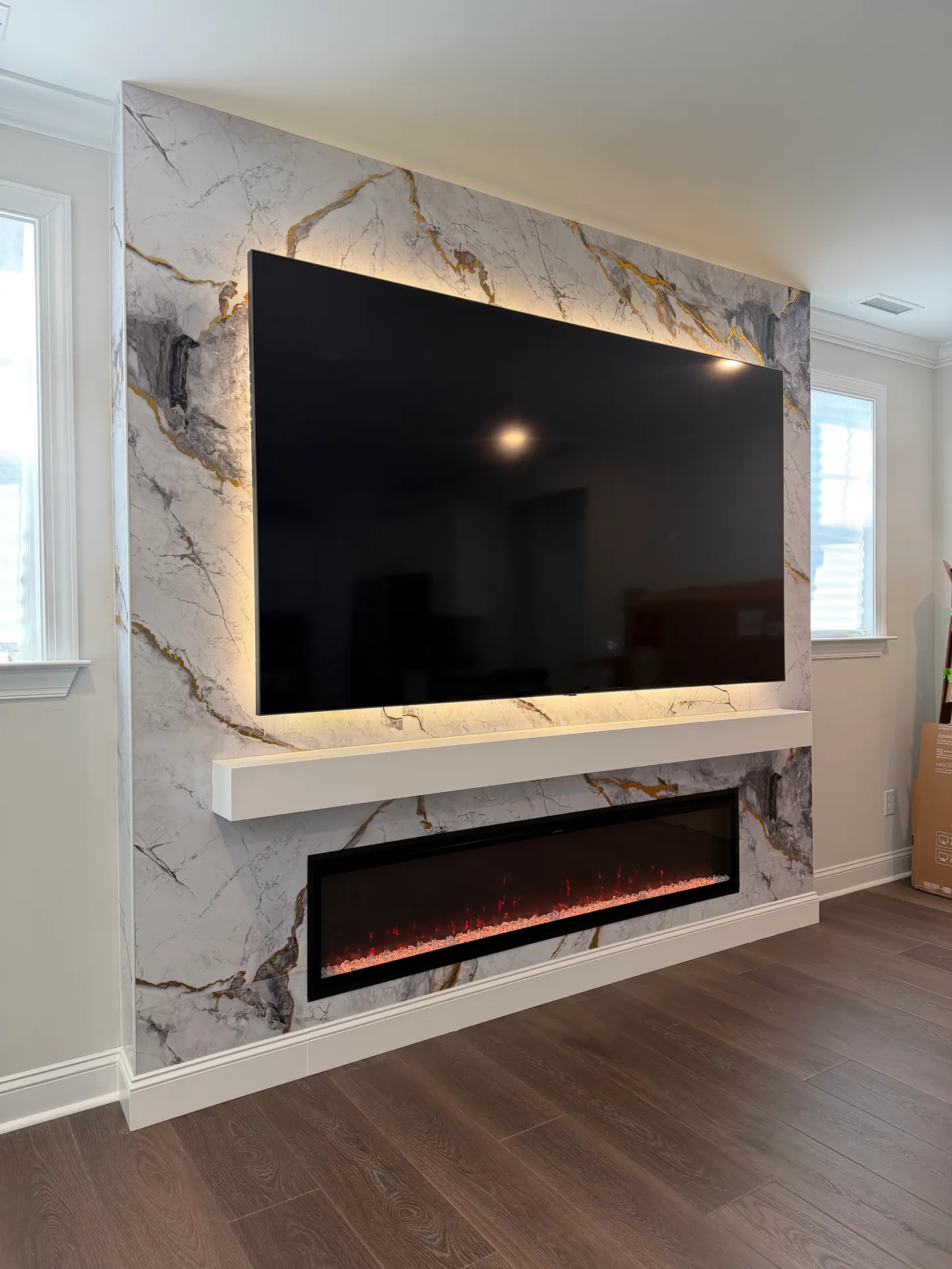 Marble-look media wall with a white floating mantel, a backlit TV and a long electric fireplace
